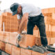 Maçon posant des briques avec précision sur un chantier, utilisant une truelle et du mortier.